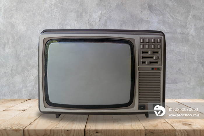 Vintage television on wooden table and cement wall texture and background.