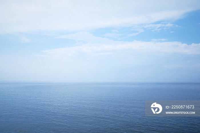 开阔的大海和多云的天空背景，朦胧的日子里平静的海水，旅行或度假的概念