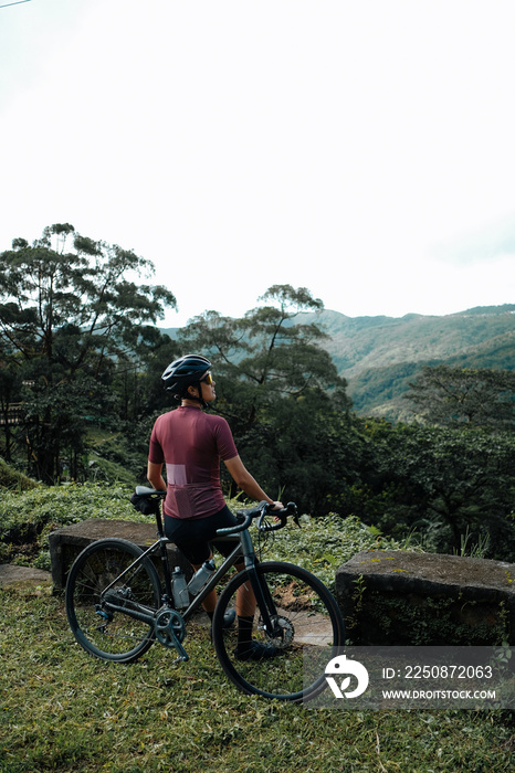 A young female cyclist looking at a view in the mountains during her bike ride.