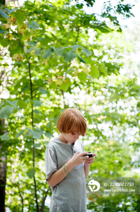 Boy using phone in forest