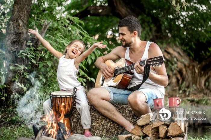 dad plays the guitar, daughter on the nature