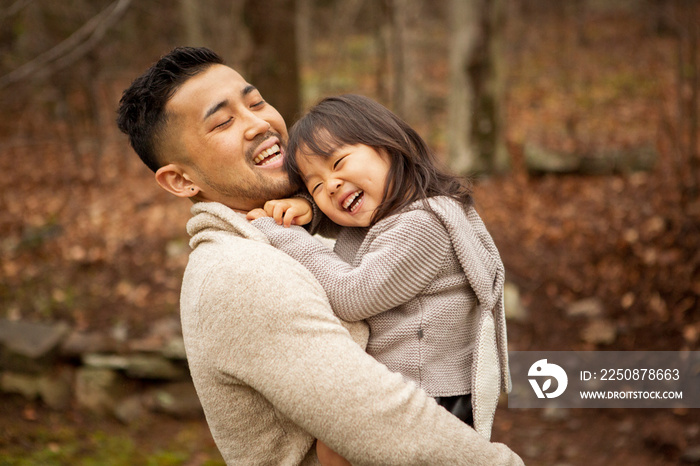 Smiling father carrying his daughter in forest