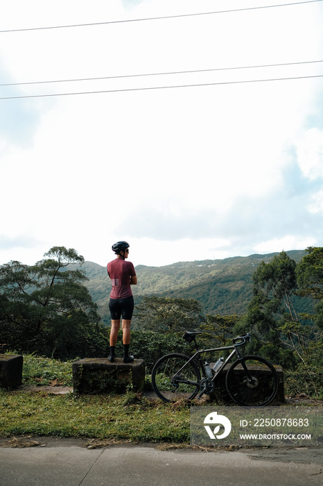 A young female cyclist looking at a view in the mountains during her bike ride.