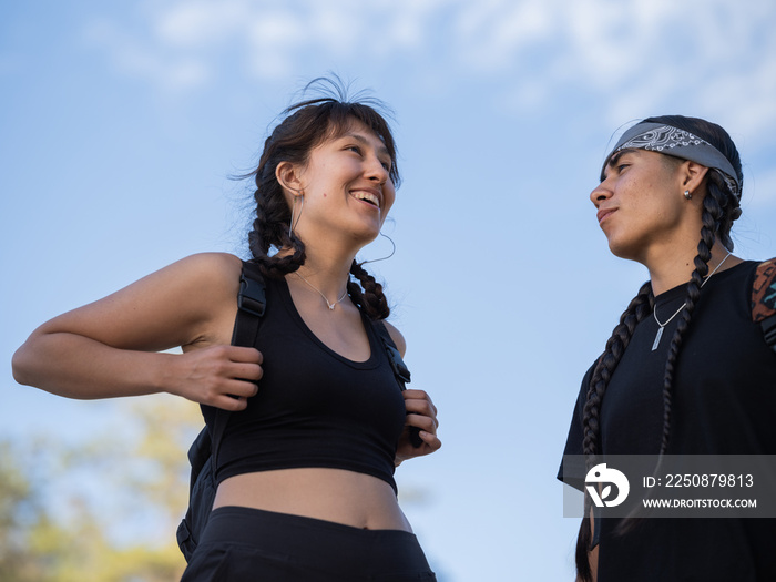 土著妇女穿着登山装备，紧紧抓住背包带，站在朋友旁边