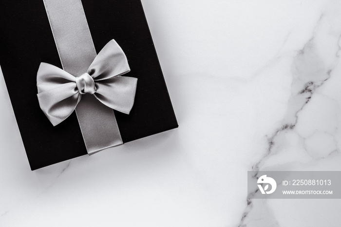 Luxury holiday gifts with silver silk ribbon and bow on marble background