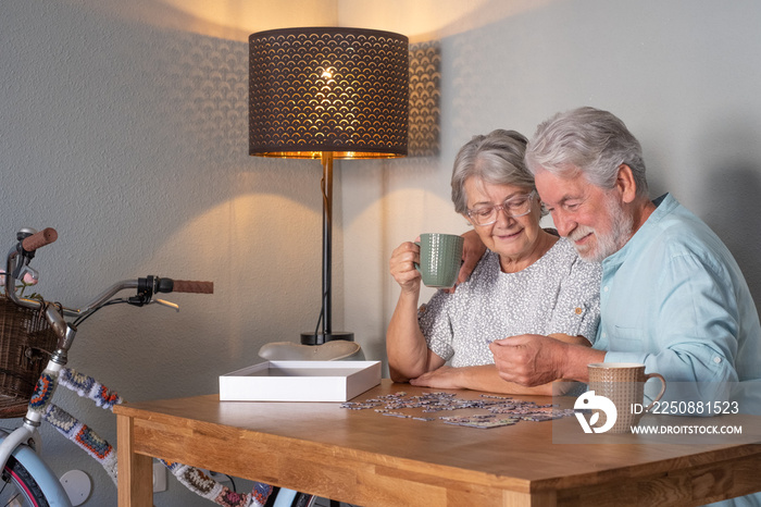 Senior couple at home spend time together doing a jigsaw puzzle on the wooden table.