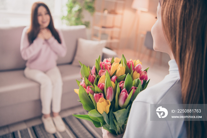 Portrait of school person arms hold flowers for mommy sitting on sofa spend holiday free time indoor