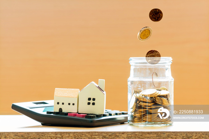 Home model put on the calculator and coin drop in the jar with growing money in the office, Business
