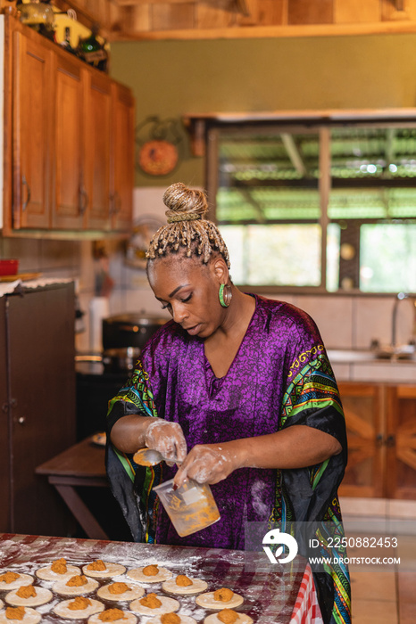 Imagen vertical de una mujer afrocaribeña en el interior de su casa preparando unos deliciosos patie