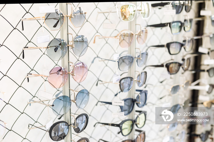 Many sunglasses rows at optical retail store. Rich assortment choice of different eyewear frames on 