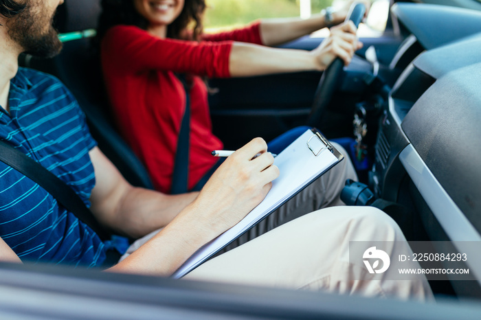 Driving school or test. Beautiful young woman learning how to drive car together with her instructor