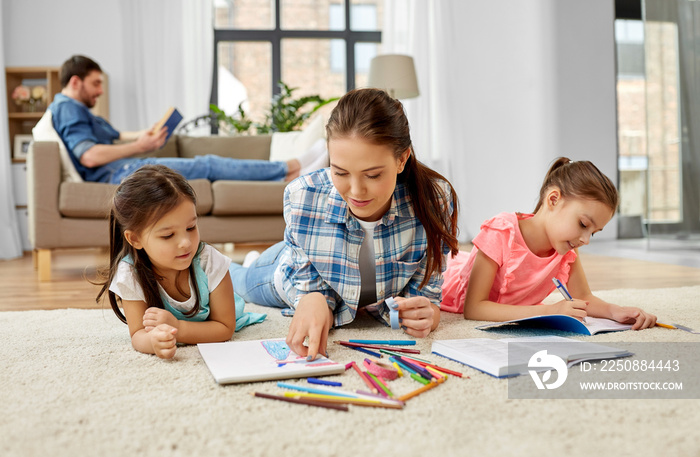 family, motherhood and leisure concept - mother spending time with her little daughters drawing and 