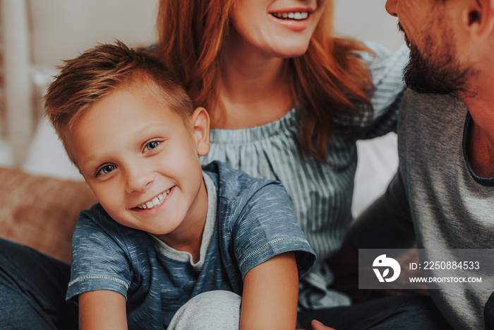 Happy son sitting on bed together with parents