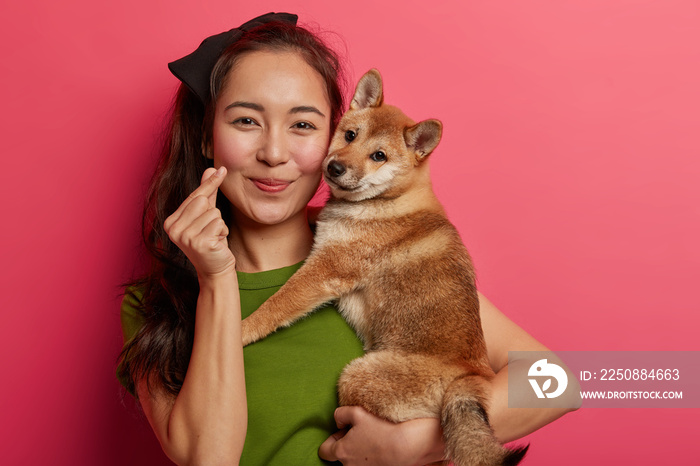 美丽的亚洲女人的肖像展示了迷你心形手势，表达了爱，拥抱了日本血统