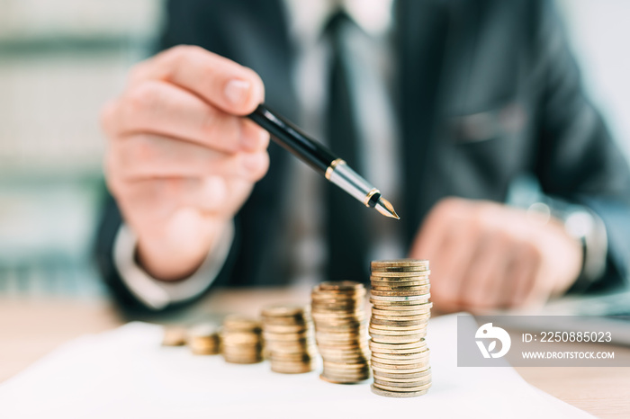 Investment return concept, businessman pointing to a coin stack at office desk