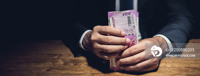 Businessman holding the Indian rupee money banknotes in dark room