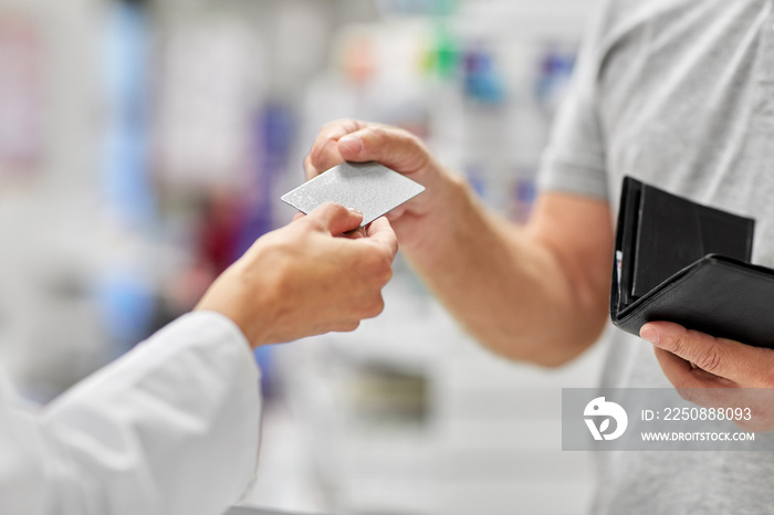 medicine, payment and finance people concept - close up of hand giving bank card to pharmacist