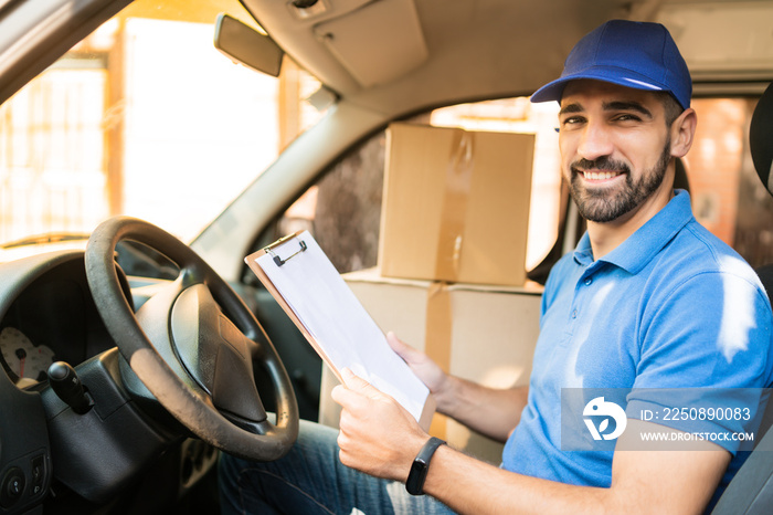 Delivery man checking delivery list in van.