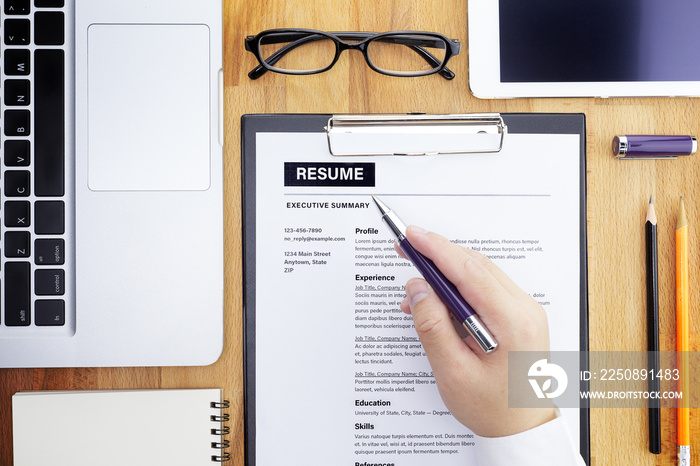 Businessman or HR Manager review a resume on his desk with Magnifier, computer laptop, digital table