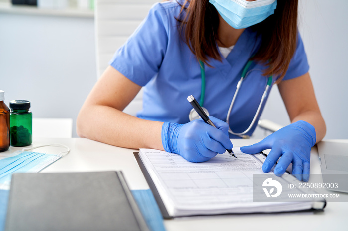 Close up of female doctor filling out medical records