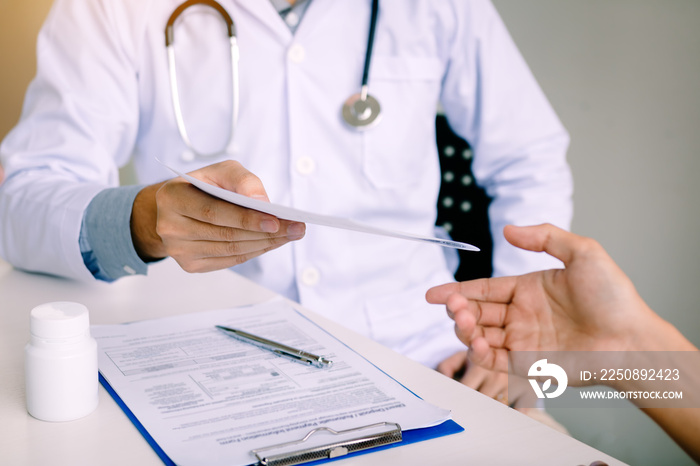 Male doctor handing a prescription to the patient.