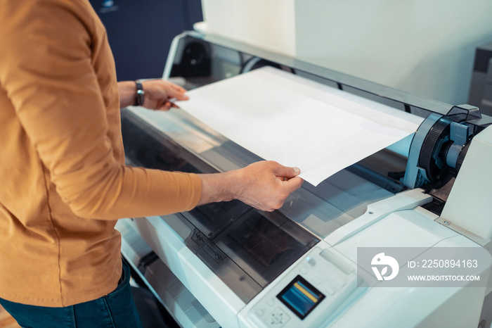 Close up of man wearing orange sweater printing posters