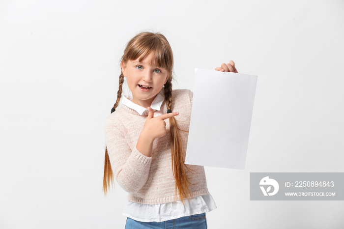 Little girl with blank paper sheet on light background