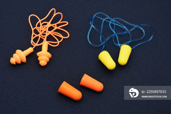 Ear plugs isolated on blue /dark background.Orange and  yellow  ear plugs isolated