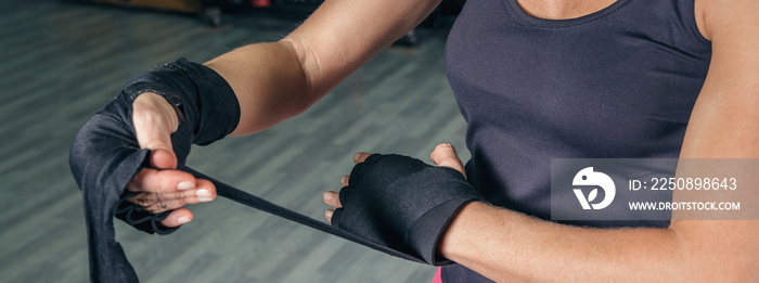 Closeup of unrecognizable sportswoman wrapping her hands with protective bandages before boxing trai