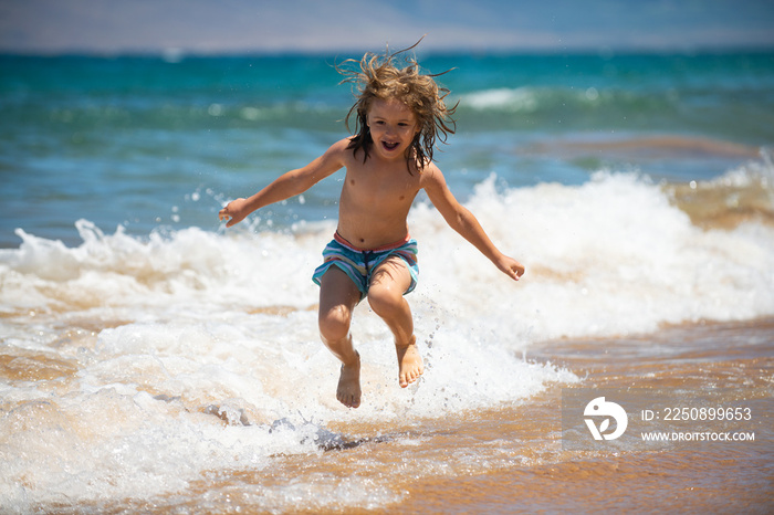 孩子在海边跳。孩子在海上度假时在海浪中跳。小男孩在热带跑步