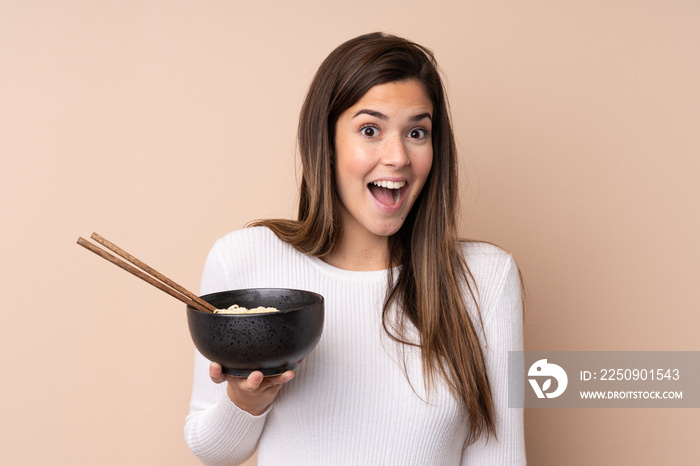 Teenager girl over isolated background with surprise and shocked facial expression while holding a b