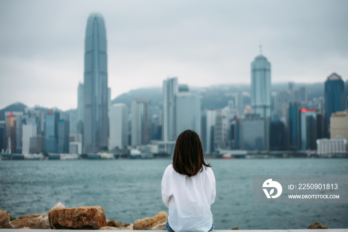 年轻女性旅行者坐着欣赏中国香港的城市景观