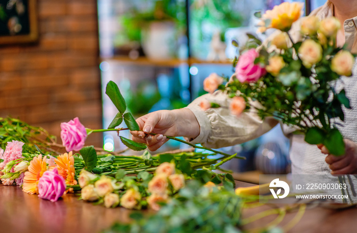 花店里一只花匠的手和一朵花放在木桌上的特写图片。装饰大师