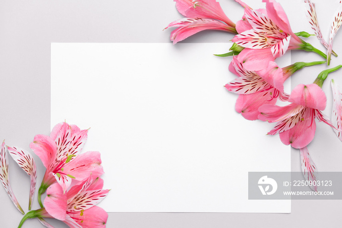 Beautiful fresh flowers and blank card on light background