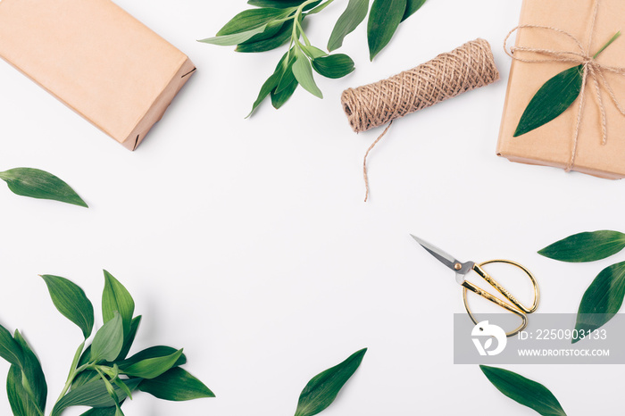 Festive flat lay frame of lush foliage, scissors, jute and boxes