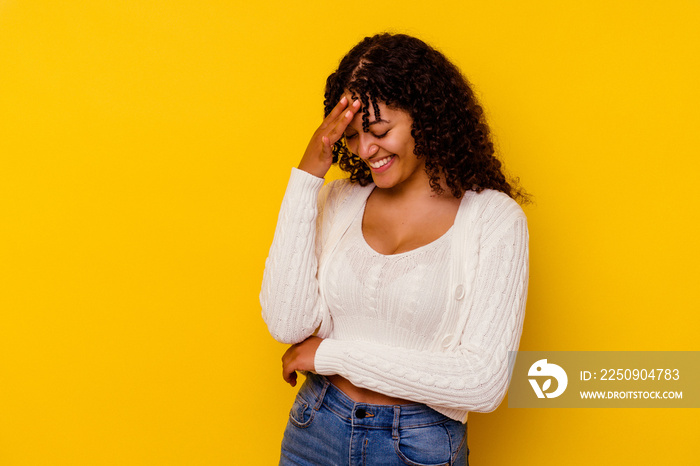 Young mixed race woman isolated on yellow background blink at the camera through fingers, embarrasse