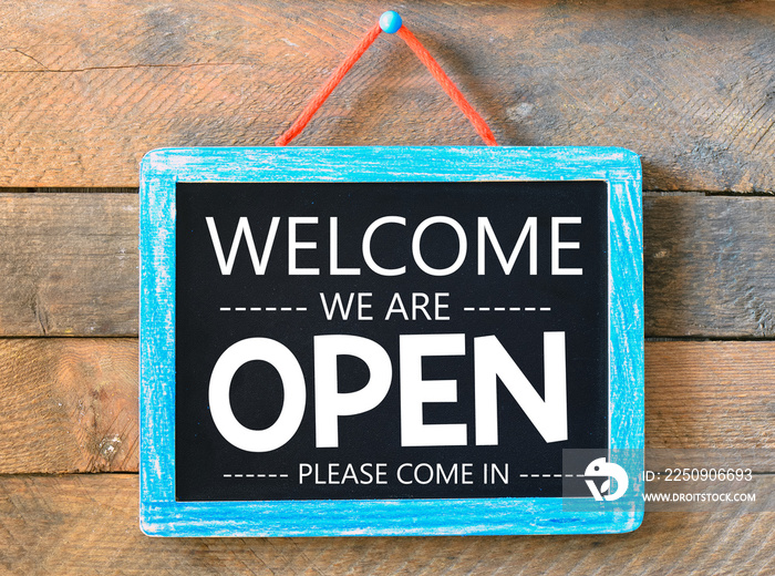 Welcome we are open words written on a chalkboard.