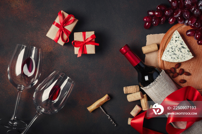 一瓶葡萄酒、礼盒、红葡萄、杏仁、开瓶器和软木塞，在锈迹斑斑的背景俯视图上