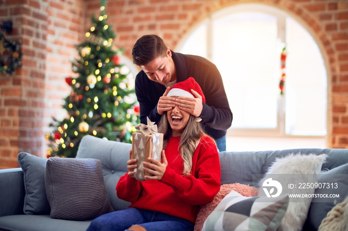 Young beautiful couple smiling happy and confident. Man covering eyes of woman surpise her with gift