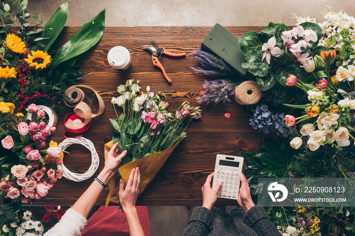 cropped image of florist wrapping bouquet in pack paper