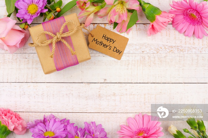 Double border of flowers with Mothers Day gift and tag against a rustic white wood background