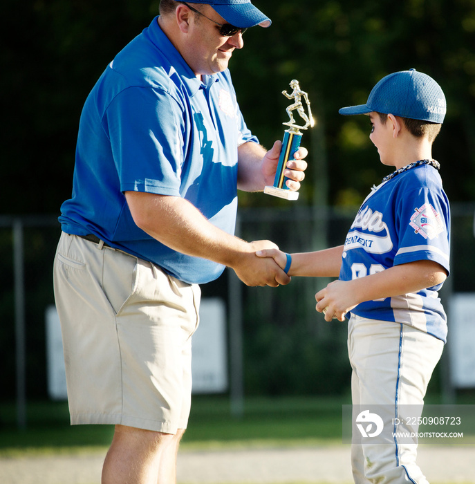 Coach presenting trophy to little league player (8-9)