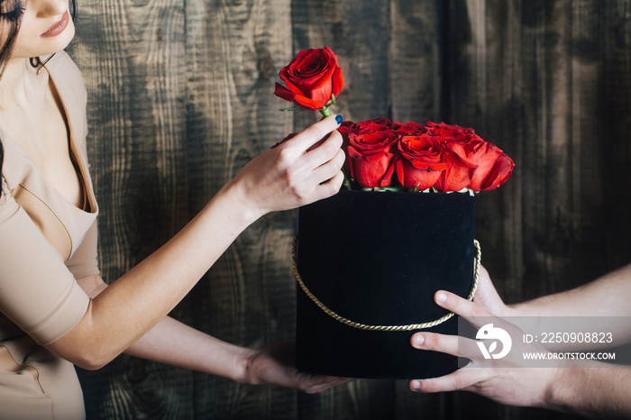 Beautiful red roses in black box in human hands