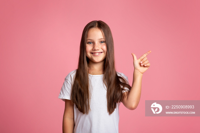 Kid with long hair presenting product. Happy little girl shows to empty space