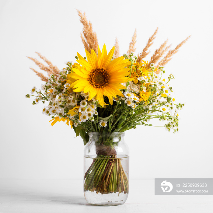 Field flowers in a glass vase. Summer bouquet of flowers on the white background