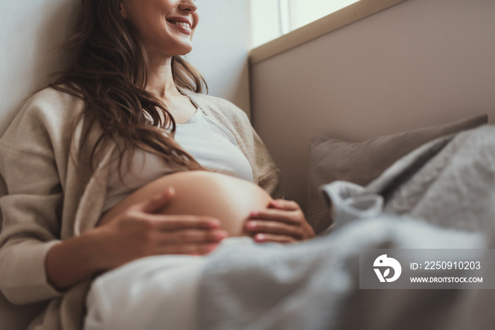 Glad future mom tuching her tummy and smiling