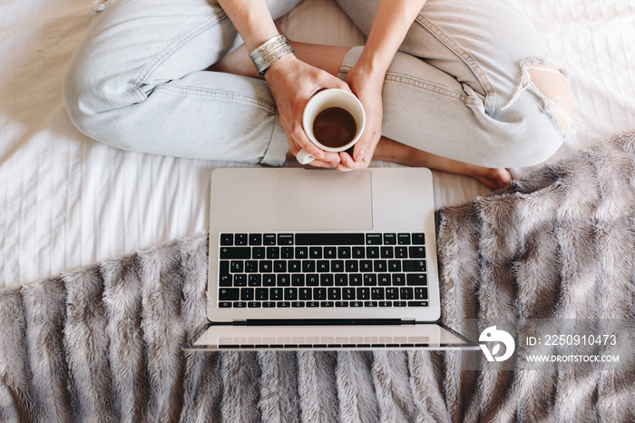 unrecognized woman drinking coffee and watching movie on her laptop