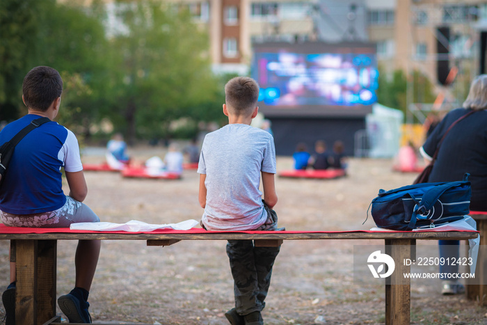 Open-air cinema. Children watching a movie on the screen of a summer cinema