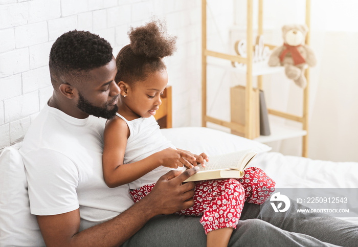 African american father teaching his little daughter how to read