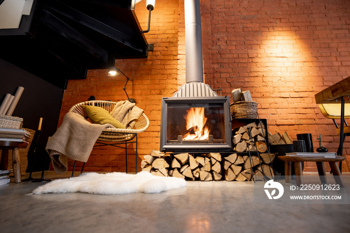 Cozy fireplace with firewood in the loft style home interior with brick wall background, burning fir